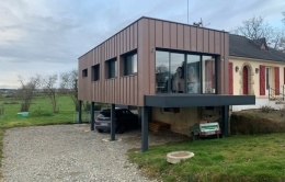 Extension bois sur pilotis bardage zinc coloris rouge